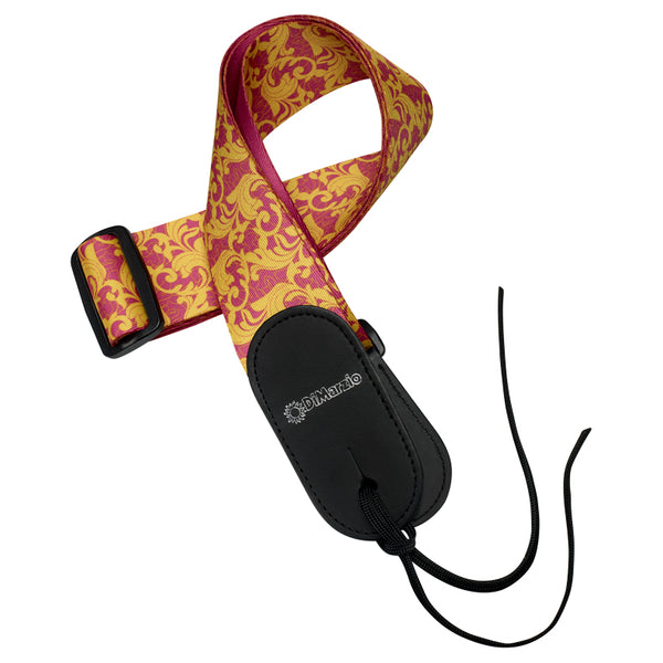 Image of a guitar strap against white background. the guitar strap has black at the bottom where it attaches to the guitar and in white says "DiMarzio". the strap is pink and gold with a leafy swirled pattern.