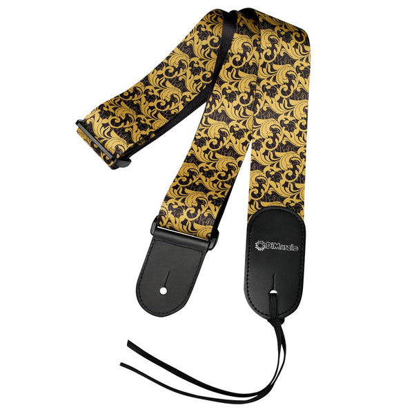  Image of a guitar strap against white background. the guitar strap has black at the bottom where it attaches to the guitar and in white says "DiMarzio". the strap is black and gold with a leafy swirled pattern.