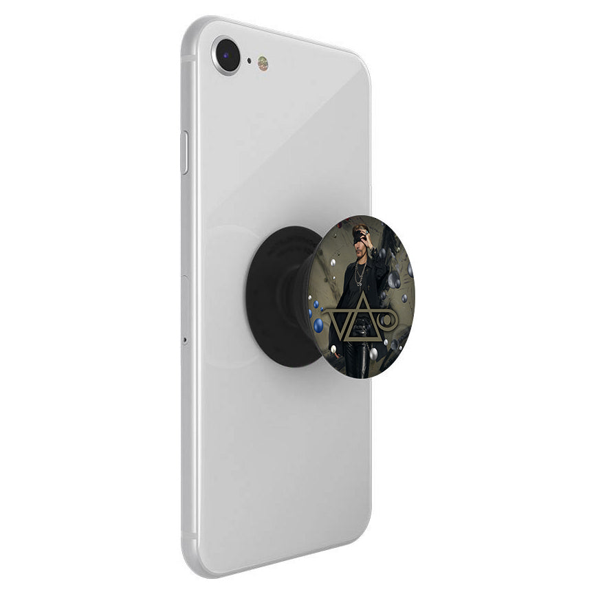 A white smartphone with a black phone holder featuring a photo of a person in dark clothing and sunglasses, accented by inviolate gold geometric design. The phone socket is branded Steve Vai.