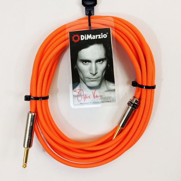 image of a neon orange guitar cable with gold ends against white background. the black cable has a tag that features a black and white photo of steve vai, photographed from the neck up. above steve's head reads "dimarzio" in white text. below steve in red cursive are the words "steve vai".