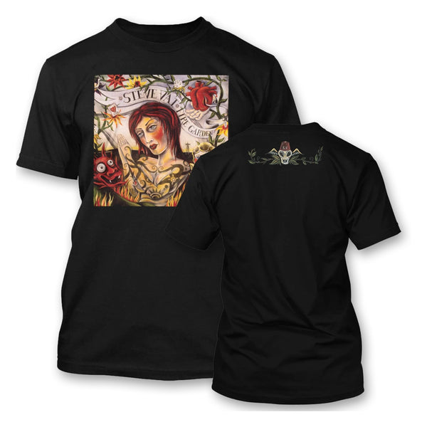 Image of the front and back of a black tshirt against white background. the front has a drawn image of a woman looking towards a cartoon devil face. above her head in a white banner with black text reads "steve vai, fire garden". there is a heart above this in red and green flower stems. the back of the shirt has a rectangular design across the top shoulder area of a drawing that looks like a skull. 