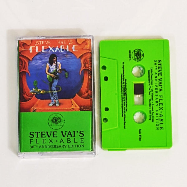 image of a green cassette and clear cassette tape case with steve vai's flexible artwork on it.  the artwork is red with a blue circle in the center. standing by the blue circle is steve vai playing a green guitar. the neck of the guitar droops down. swirling around steve is an alien in a small ship. above this in blue and white text reads "steve vai's flexable". 