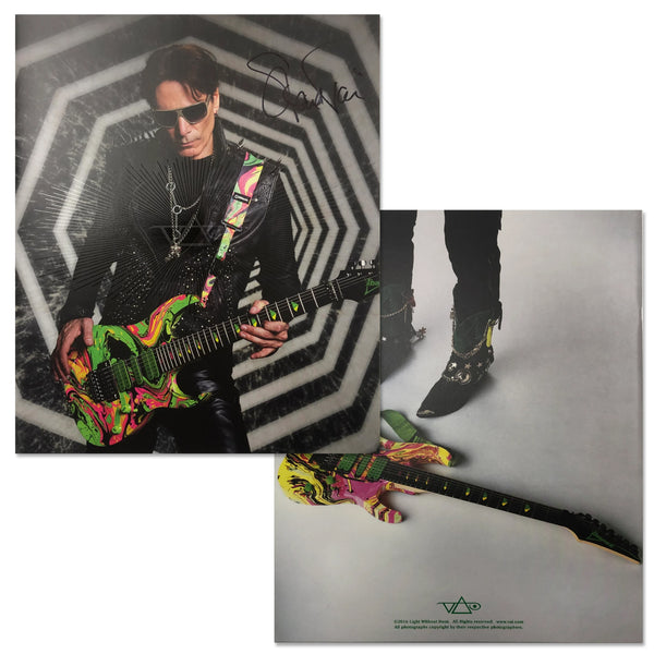 Image of the front and back of steve vai passion and warfare signed tour program. The front is a photo of steve vai in all black, playing a green, yellow, black, pink, and orange abstract marbled guitar. Steve signed his name to the right of the photo of himself. the back is a photo of the electric guitar lying on a white floor, with steve vai's black boots behind it.