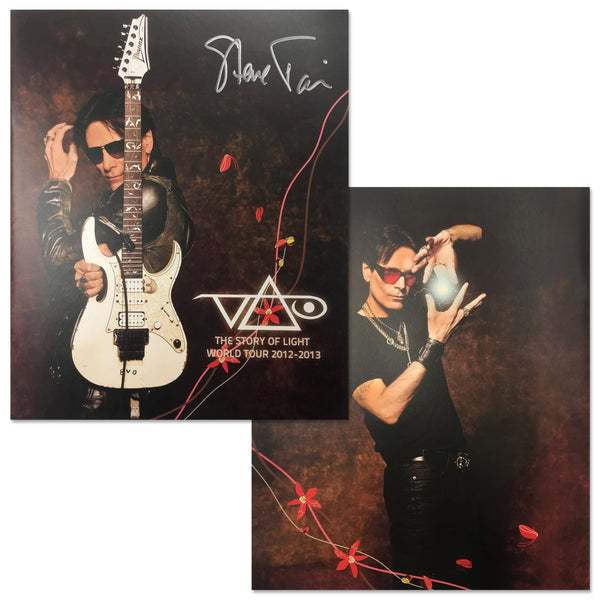 Image of the front and back of a signed steve vai tour program against white background. the front is an image of steve vai in all black, with sunglasses over his eyes. he holds up a white electric guitar. it says the story of light, world tour 2012-2013 in white text. the back is a photo of steve vai with his hands in the air, a white orb of light in between them. steve wears red sunglasses in this. 