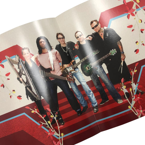 image of the inside of the steve vai signed tour program. it is a photo of steve vai posing with 4 other musicians, standing on a red carpet. they all face the camera and smile.
