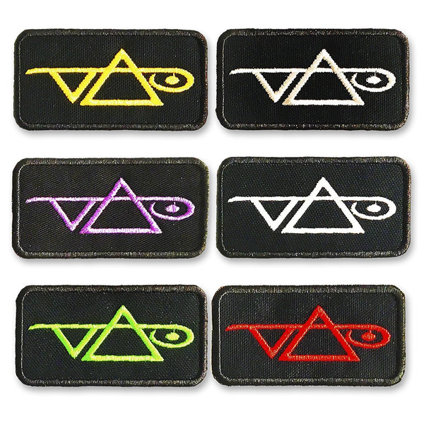 Image of 6 black rectangular patches against white background. Each patch has the steve vai logo on it, one in yellow, two in white, one in pink, one green, and one red.  The steve vai logo makes the word "vai" with an upside down triangle, a right side up one, and a line going across the triangles with a curl at the end next to the triangle that is upright. 
